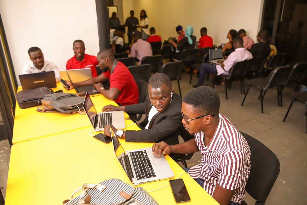 A group of people sitting at tables with laptops.